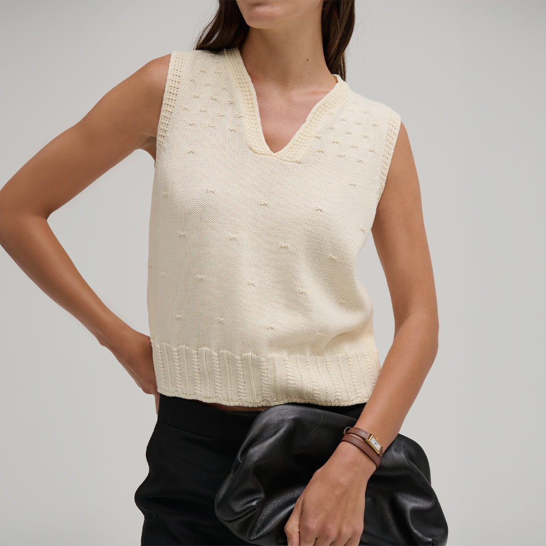 Woman wearing a cream sleeveless Nina Split Neck Tank by Margaret O'Leary against a gray background