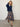 Woman wearing a Natalya Pleated Skirt by Margaret O’Leary, a multicolour plaid pleated skirt styled with a navy cardigan on a plain background.