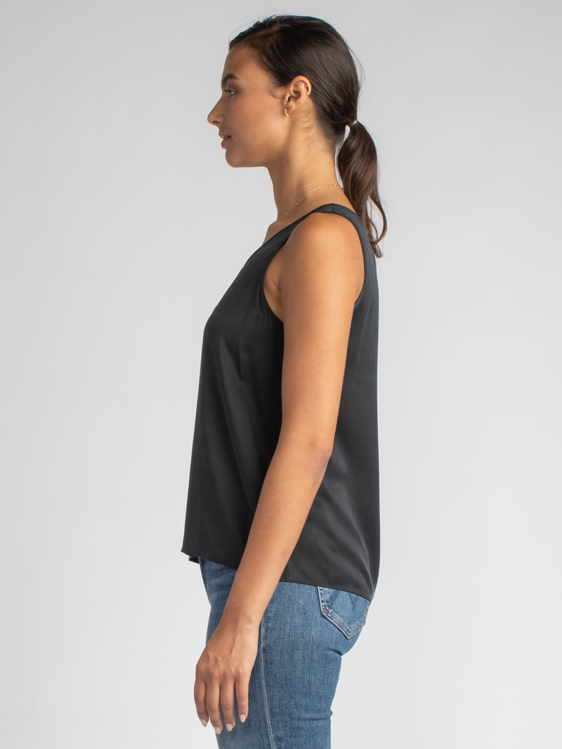 Side view of the model wearing a black tank and a pair of jeans.