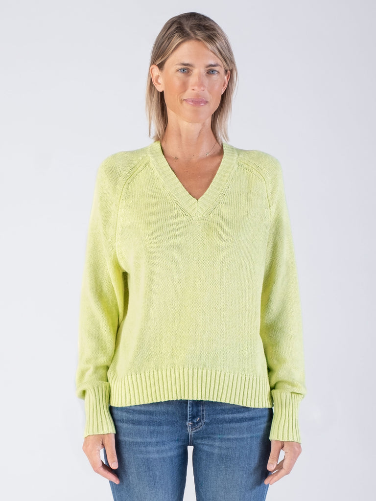 Model wearing a cotton/hemp mixed loose gauge vee pullover in lemongrass color and a pair of jeans.