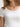 Woman wearing a white Stretch Scoop Tee and grey pants by Margaret O'Leary against a plain background
