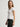 Woman wearing a white Stretch Scoop Tee and grey pants by Margaret O'Leary against a plain background