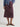 Woman wearing a printed button down Roan Shirt and purple midi Sandra skirt by Margaret O'Leary against a grey backdrop.