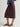 Woman wearing a printed button down Roan Shirt and purple midi Sandra skirt by Margaret O'Leary against a grey backdrop.