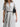 Woman wearing a white and gray striped Tiered VNeck Dress with a black belt against a white background