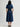 Woman wearing a Navy Tiered V-Neck Dress by Margaret O'Leary against a grey studio wall.
