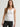 Woman wearing a white Stretch Scoop Tank and grey pants by Margaret O'Leary against a plain background