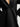 Close-up of a black cashmere St. Germaine Coat by Margaret O'Leary with a pearl pin on a white background