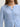 Woman wearing a cashmere-silk Coco cardigan by Margaret O'Leary and dark blue jeans on a plain background
