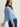Woman wearing a cashmere-silk Coco cardigan by Margaret O'Leary and dark blue jeans on a plain background
