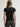 Woman wearing a black Stretch Scoop Tee and grey pants by Margaret O'Leary against a plain background