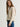 Woman wearing a cashmere-silk Coco cardigan by Margaret O'Leary and dark blue jeans on a plain background