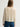 Woman wearing a cashmere-silk Coco cardigan by Margaret O'Leary and dark blue jeans on a plain background