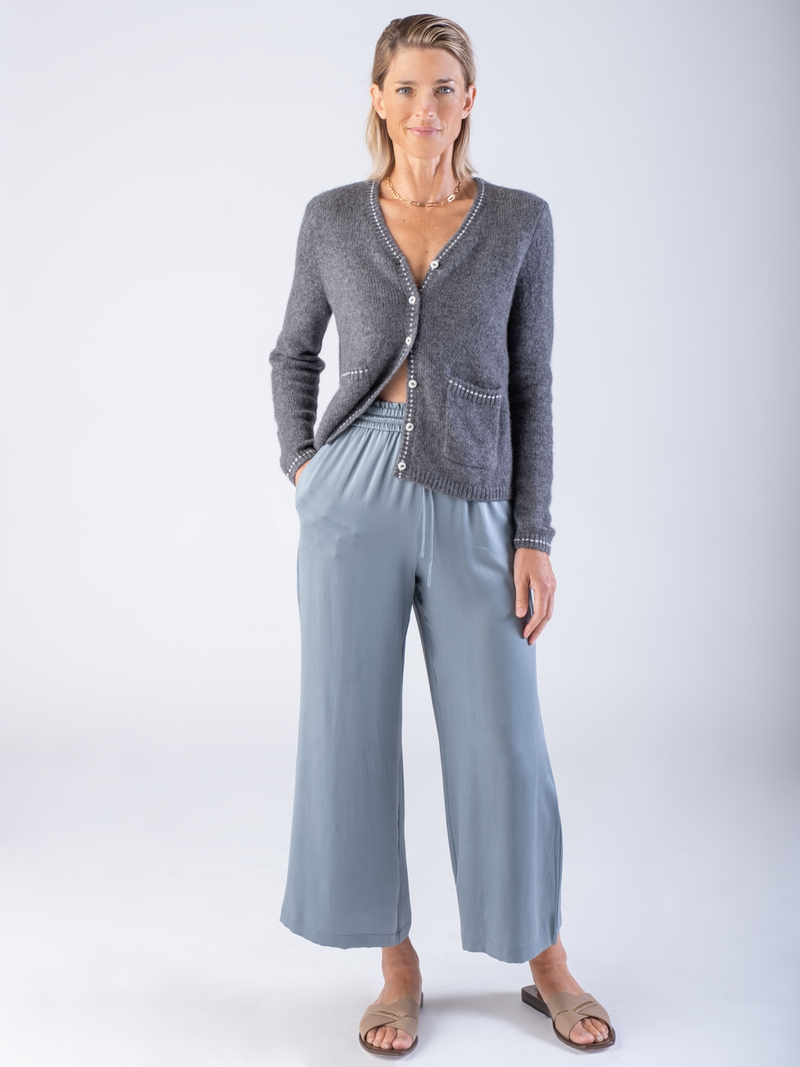 Model wearing a grey cardigan and a pair of blue pants.