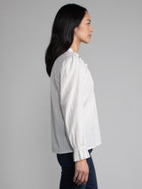 Female model wearing white blouse with ruffled neckline and cuffs. 