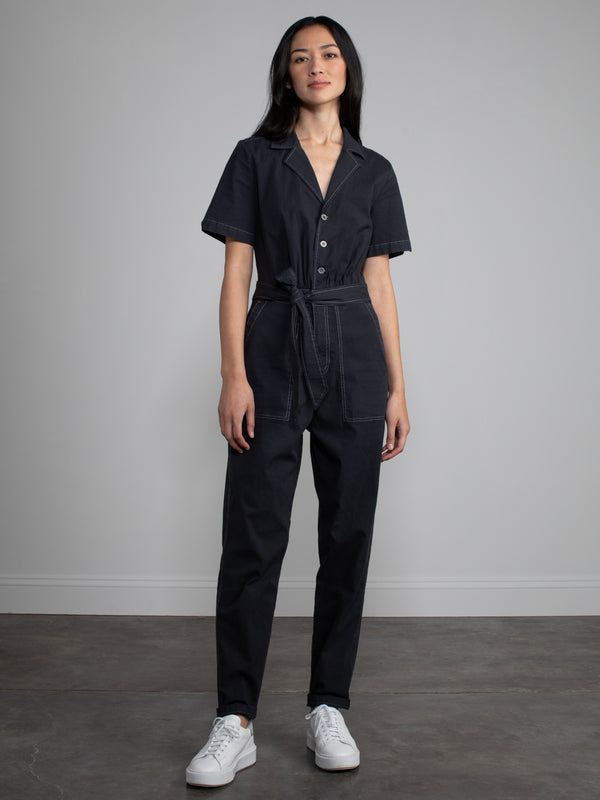 Female model wearing black jumpsuit with belt.