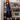 Woman in a navy satin Dayra Double V Dress by Margaret O'Leary, standing in a room with bookshelves and decor.