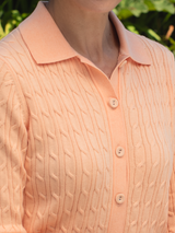 Woman wearing the Emmylou Cable Cardi in apricot by Margaret O'Leary.