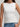 Woman wearing a white sleeveless pima tank top by Margaret O'Leary and blue jeans against a plain background