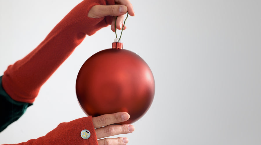 Gloved hands holding a red ornament.