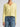 Person wearing a light green Cashmere Vee Cardigan by Margaret O'Leary and blue jeans on a plain background