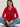 Woman wearing a red cardigan and blue jeans sitting on a white surface.