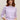 Woman wearing a purple Cara Cashmere Pullover Sweater by Margaret O'Leary and blue jeans against a beige background
