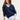 Woman wearing a cotton boucle navy Relaxed Vee Pullover by Margaret O'Leary and white pants against a plain background