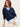 Woman wearing a cotton boucle navy Relaxed Vee Pullover by Margaret O'Leary and white pants against a plain background