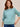 Woman wearing a cotton Sage Lola Pullover by Margaret O'Leary against a beige background