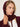 Woman wearing a Cashmere Snood by Margaret O’Leary, a burgundy hooded snood with drawstrings styled with a burgundy knit cardigan.