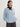 Woman wearing a light blue Diedre Cable Pullover Sweater by Margaret and burgundy cashmere triangle scarf by Margaret O'Leary over a white shirt on a plain background