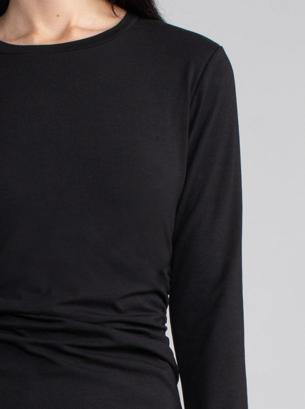 Female model wearing midi black dress with long sleeves. 