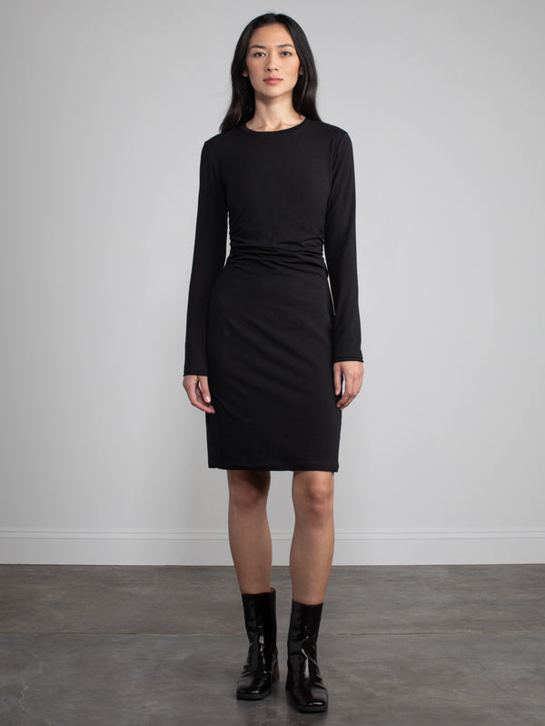 Female model wearing midi black dress with long sleeves. 