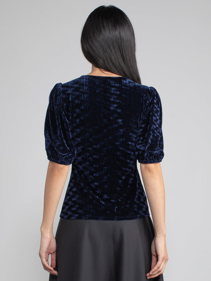 Woman wearing blue velvet blouse with corduroy effect. 