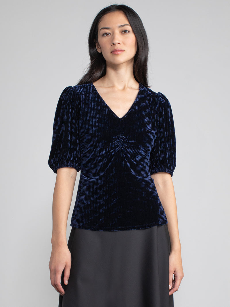 Woman wearing blue velvet blouse with corduroy effect. 