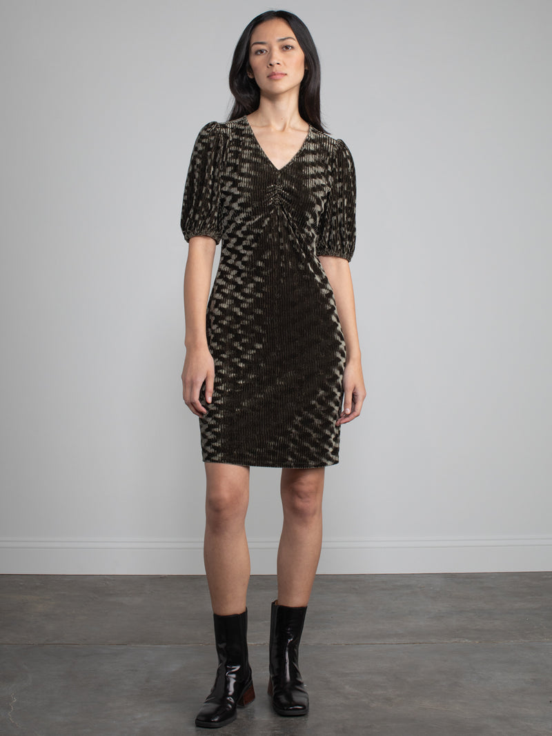 Woman wearing green velvet midi dress with corduroy effect. 