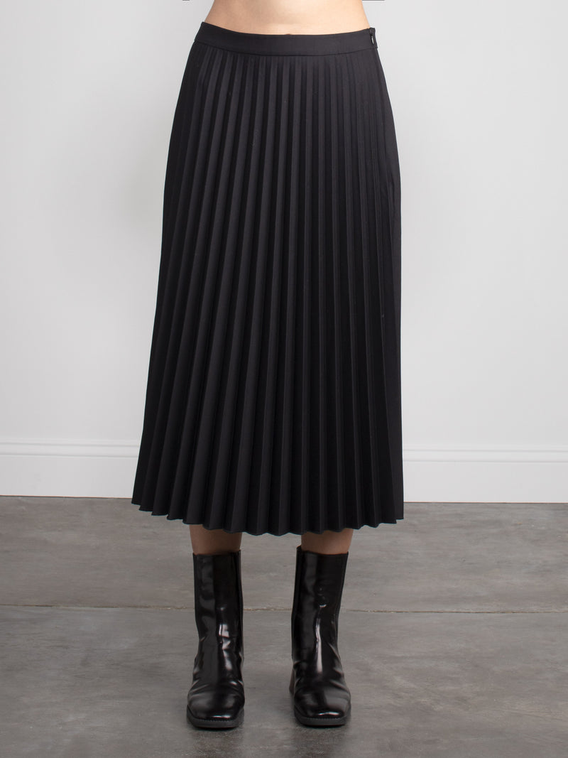 Woman wearing a black pleated skirt.