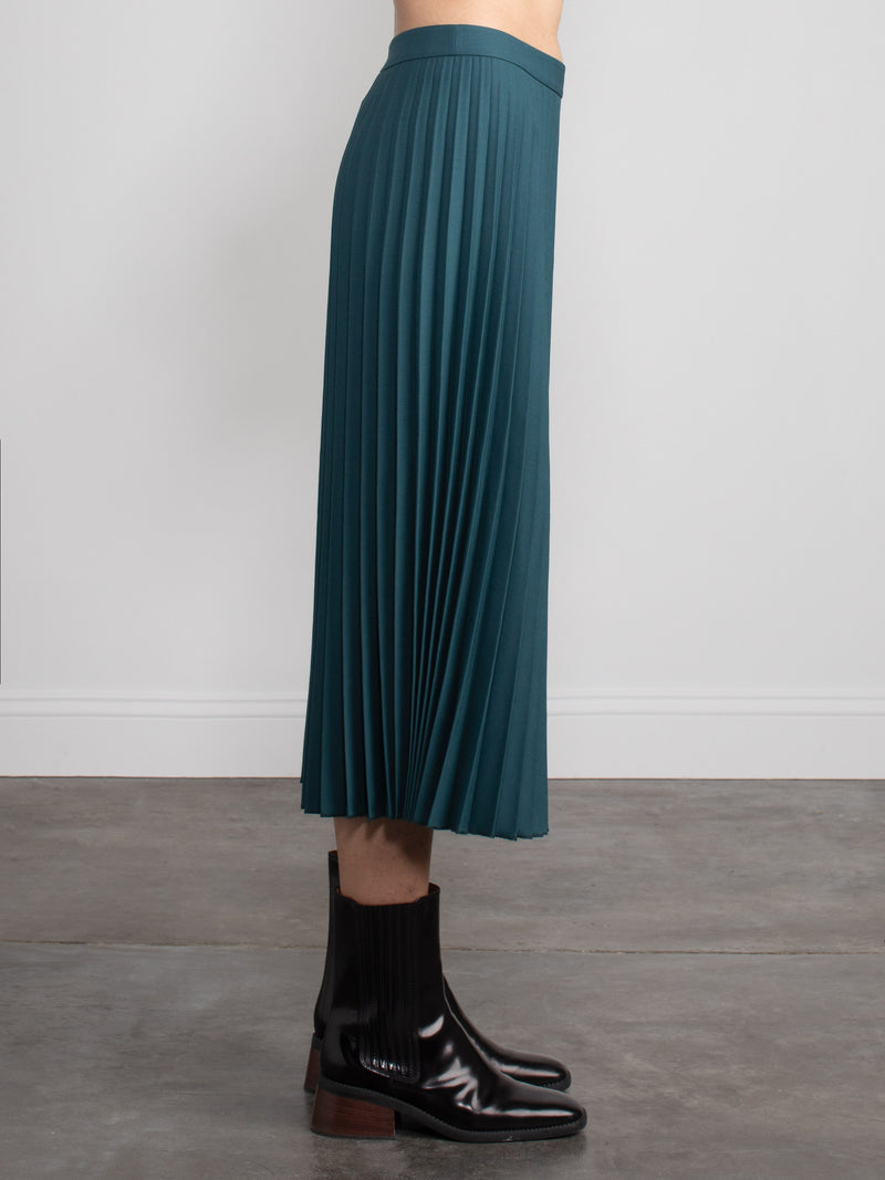 Woman wearing a green pleated skirt.