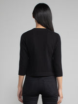 Woman wearing a black cropped cashmere cardigan.