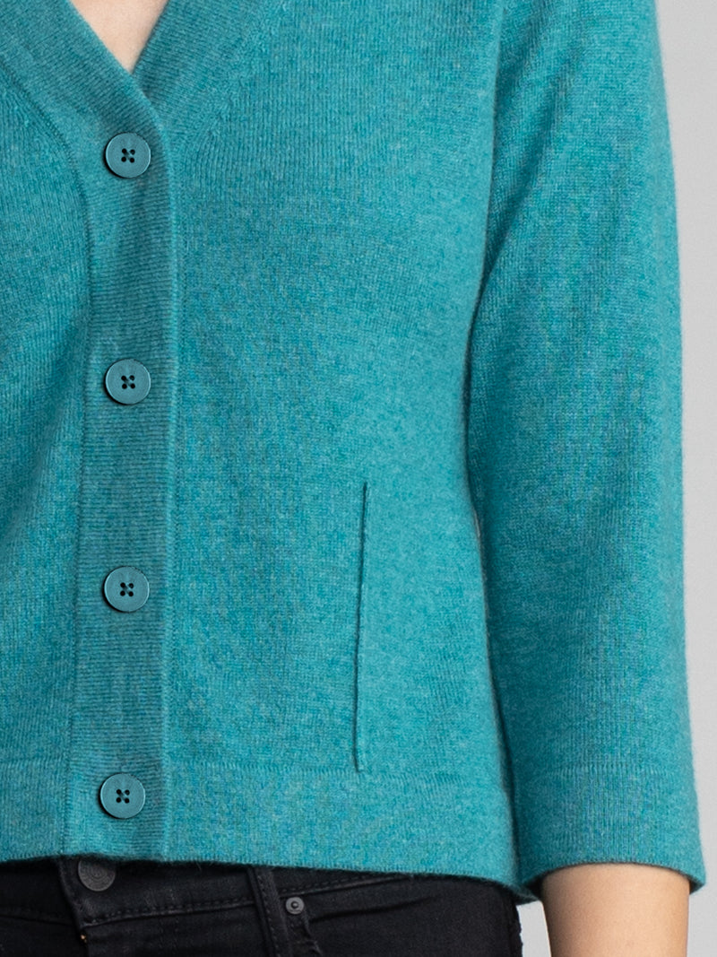 Woman wearing a teal cropped cashmere cardigan.