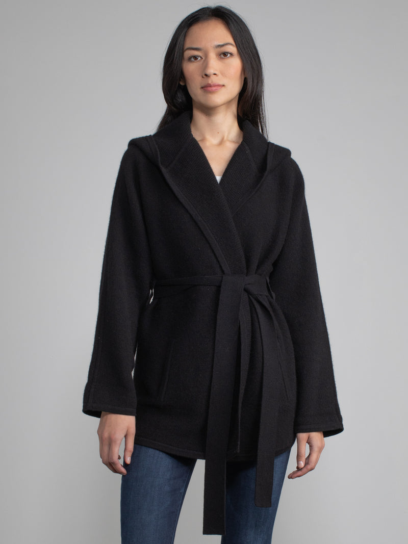 Female model wearing a black hooded jacket with a belt.