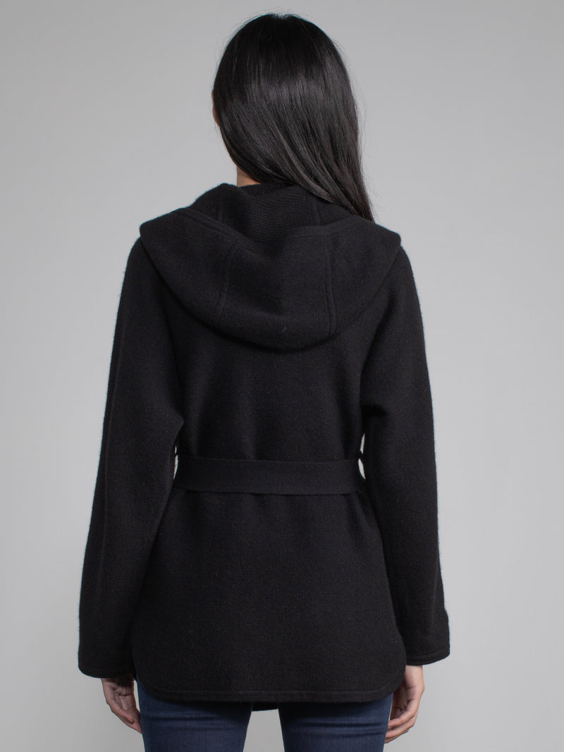 Female model wearing a black hooded jacket with a belt.