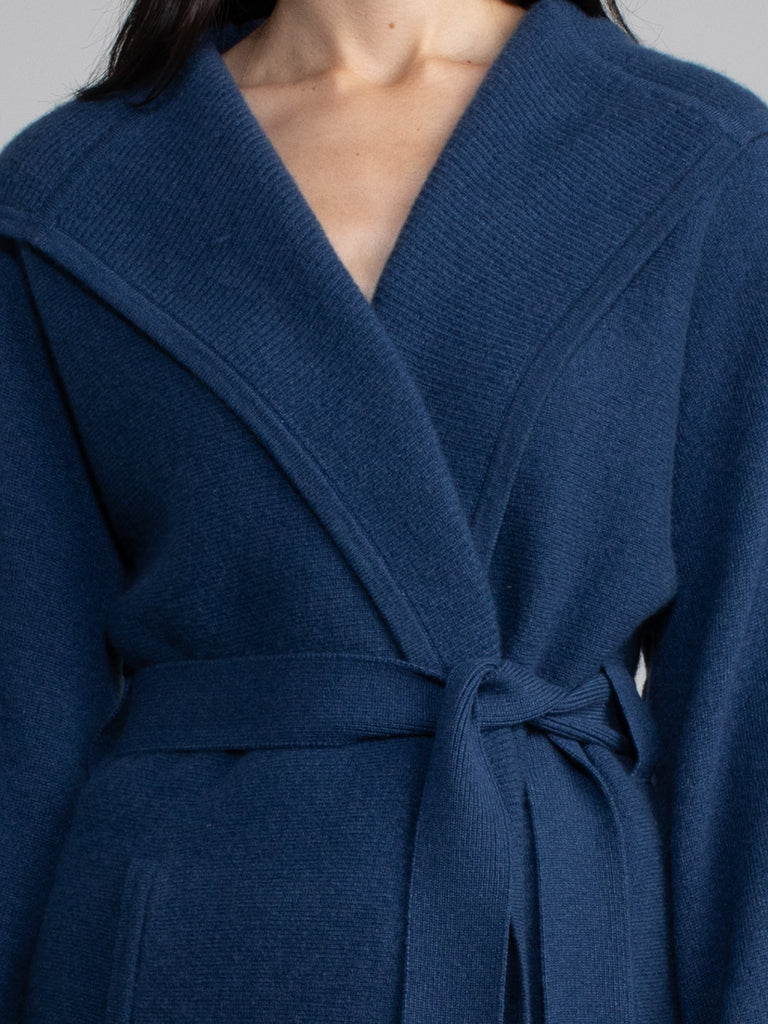 Female model wearing a blue hooded jacket with a belt.
