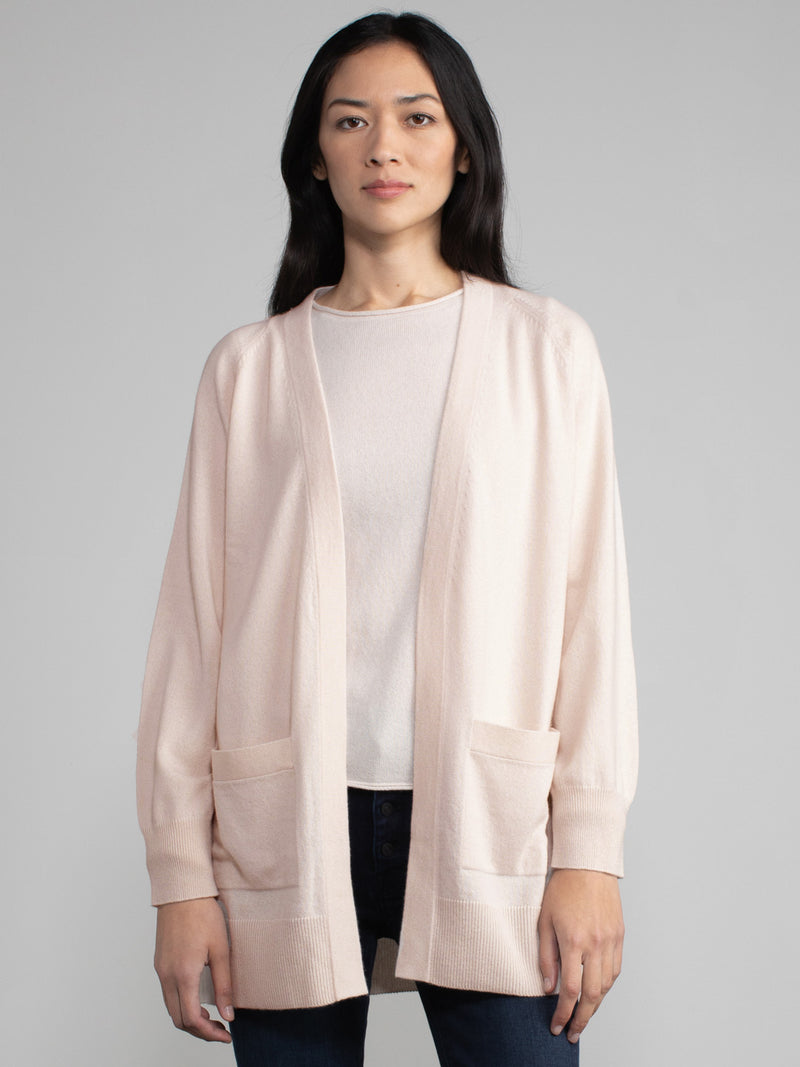 Woman wearing a matching light pink cashmere t-shirt and duster set.