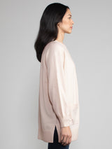 Woman wearing a matching light pink cashmere t-shirt and duster set.