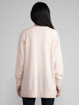 Woman wearing a matching light pink cashmere t-shirt and duster set.