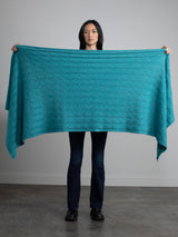 Woman holding a teal cable cashmere wrap.