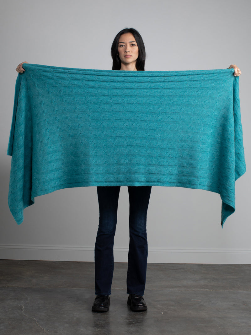 Woman holding a teal cable cashmere wrap.