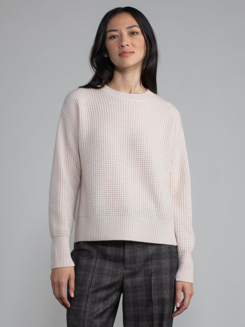 Female wearing light pink waffle stitched pullover.